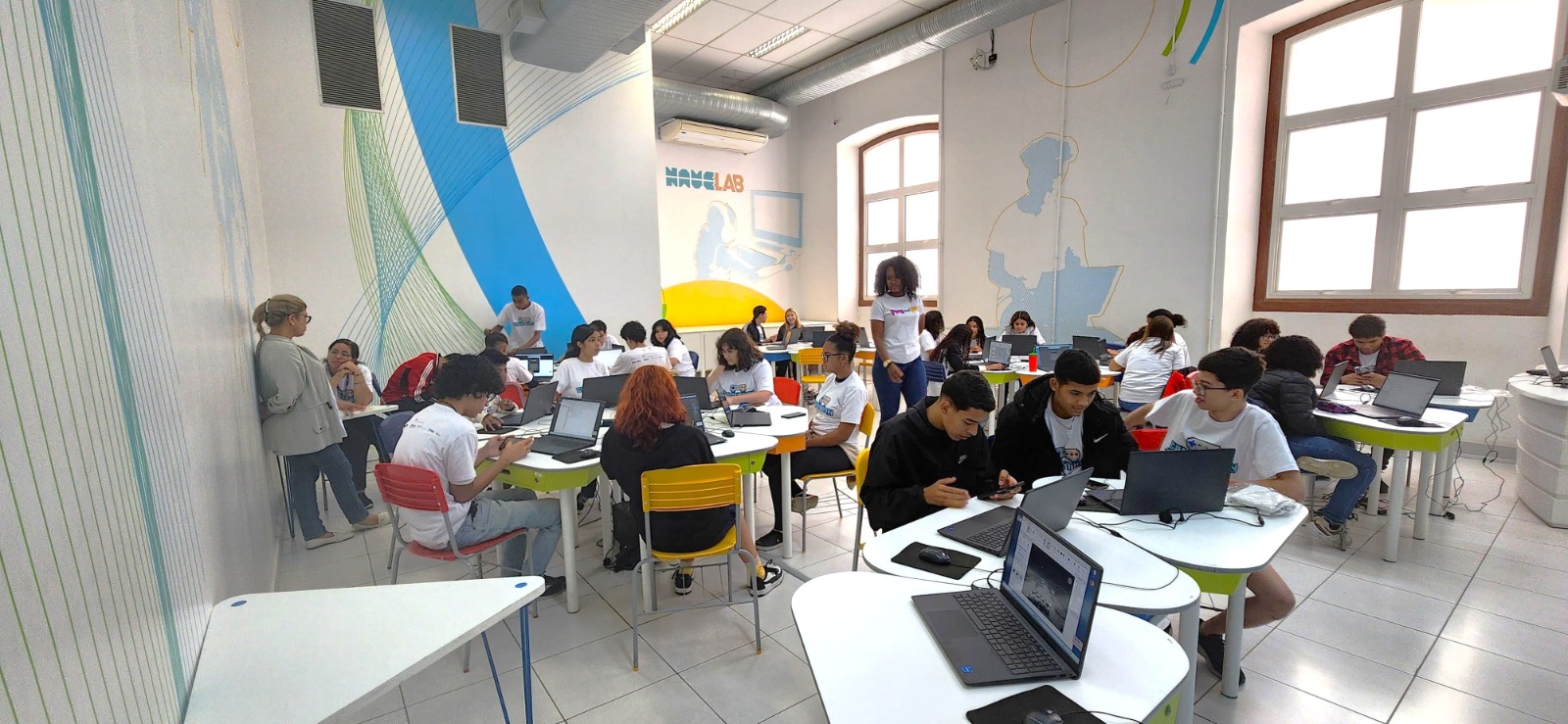 Turma de adolescentes da Plug and Plus usando laptops em um laboratório NaveLab das Naves do Conhecimento