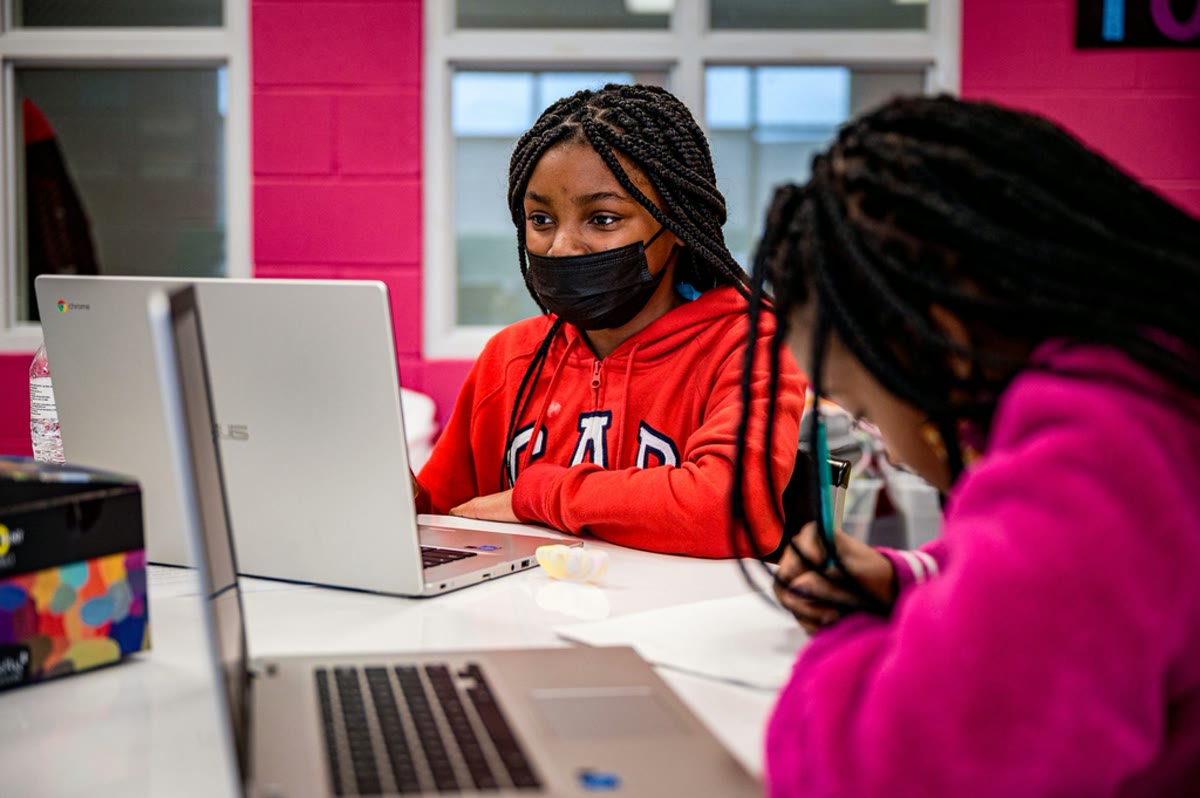 Meninas desenvolvendo projetos em laptops durante uma oficina