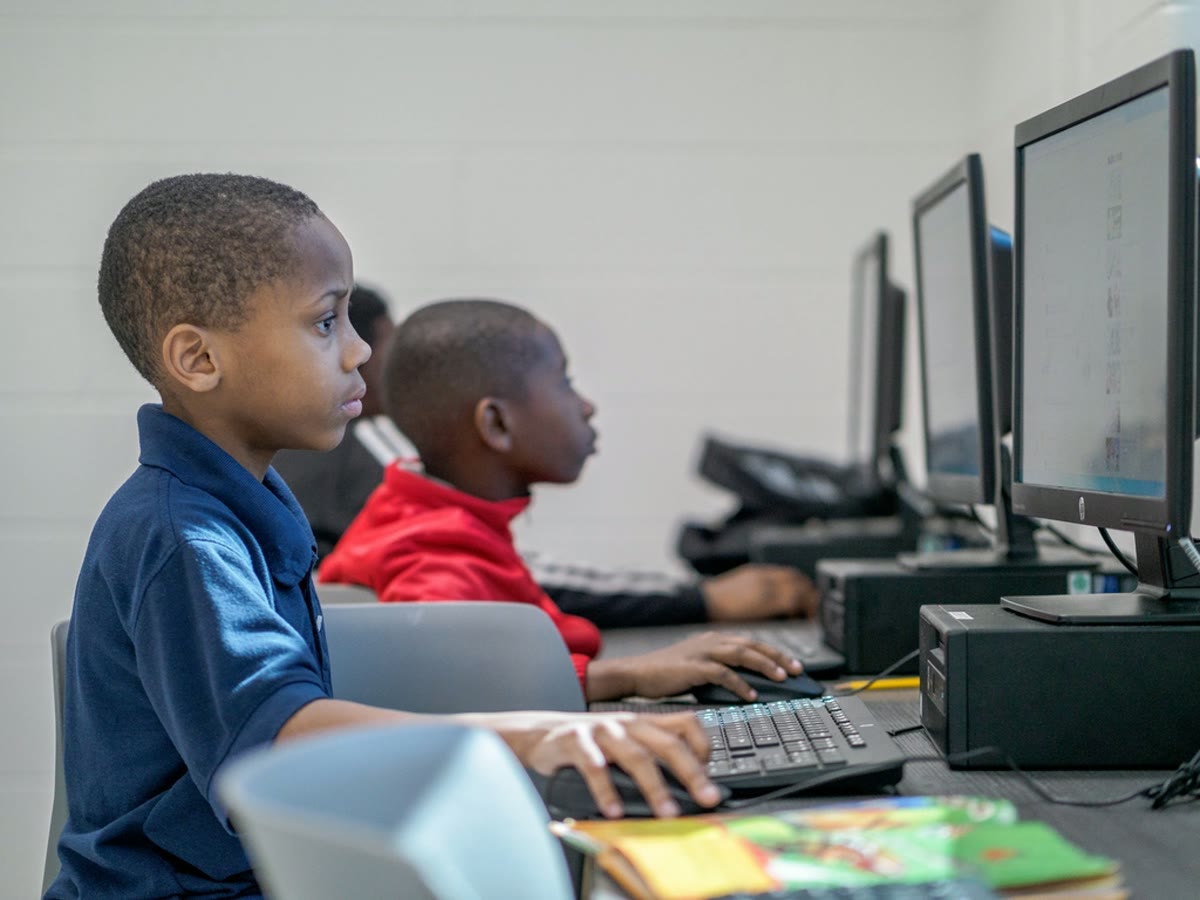 Crianças criando jogos em computadores durante uma oficina